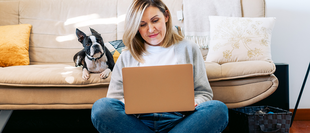 woman on computer with dog on couch