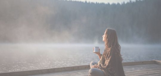 Woman sitting on dock, drinking coffee